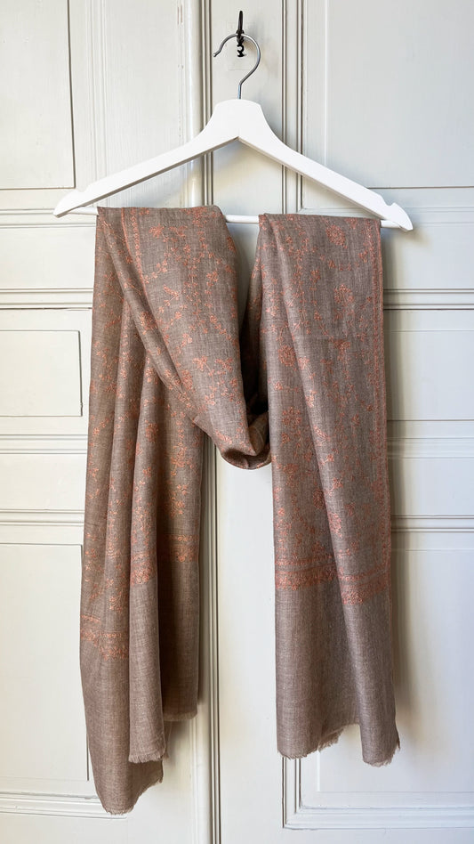 Pashmina Stole with Jaalidar Embroidery. The stole measures 74x202 cm, offering ample elegance and versatile styling options. Its natural taupe base is adorned with exquisite rose gold Jaalidar embroidery, showcasing the refined and intricate artistry that Kashmir is renowned for. 