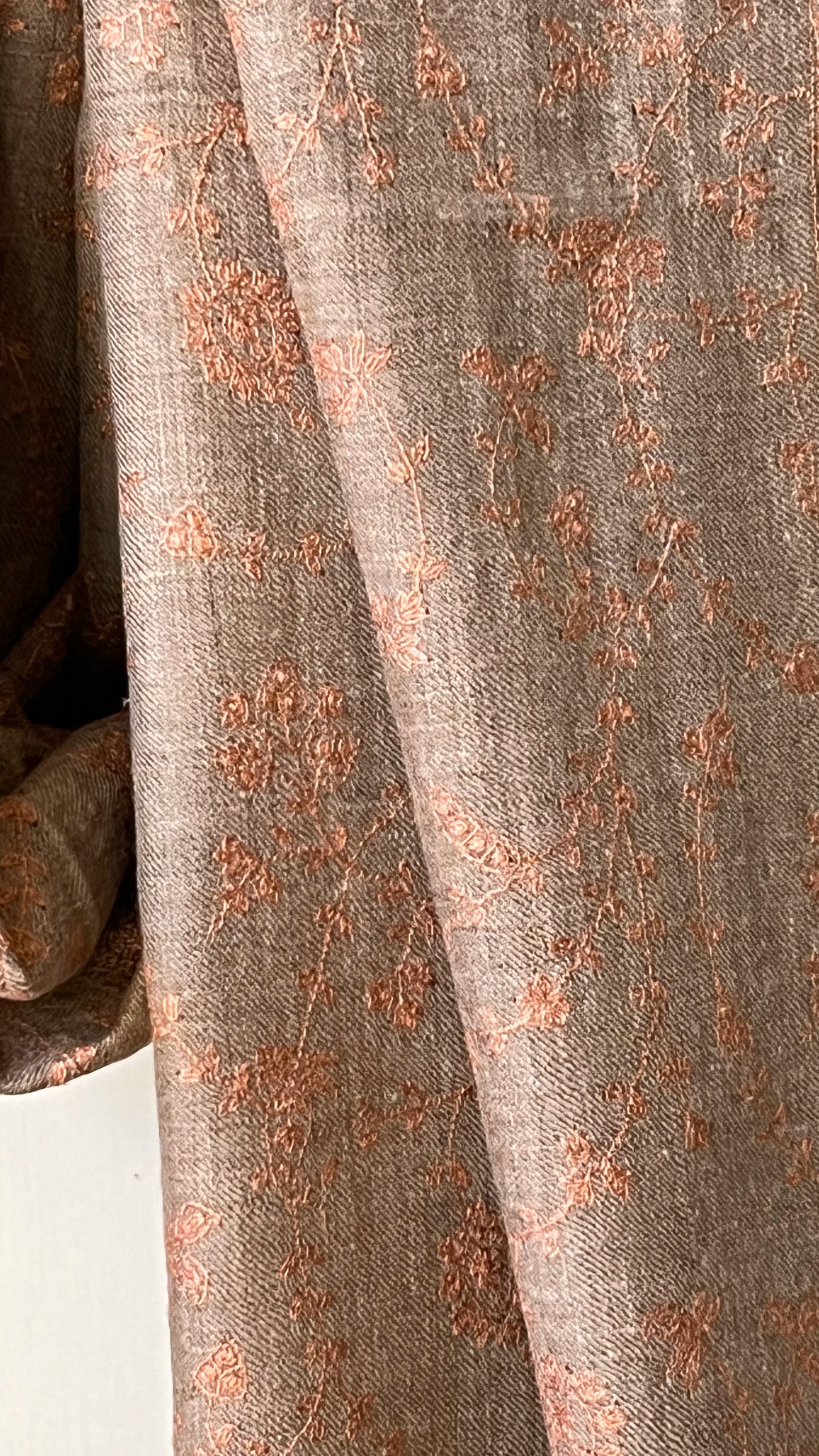 Pashmina Stole with Jaalidar Embroidery. The stole measures 74x202 cm, offering ample elegance and versatile styling options. Its natural taupe base is adorned with exquisite rose gold Jaalidar embroidery, showcasing the refined and intricate artistry that Kashmir is renowned for. 