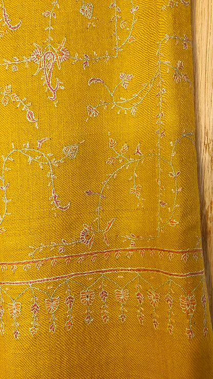 Exquisite Pashmina stole crafted from rare Yangir yarn, sourced from Himalayan Ibex, measuring 70x200 cm. Features a warm mustard base with hand-embroidered, deep burgundy Jaalidar motifs, creating a lace-like design that radiates elegance. Its exceptional softness and subtle sheen highlight the interplay of colors and textures, making it versatile for both semi-casual and formal wear.
