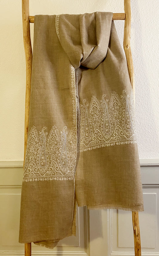 This pashmina is handcrafted with 100% cashmere on a handloom in Srinagar, India. The shawl is embellished with exquisite Sozni embroidery, featuring intricate patterns in white highlighted with subtle shades of light blue, giving it a distinct and sophisticated character. It's a piece of wearable art that brings the luxury and heritage to your wardrobe.