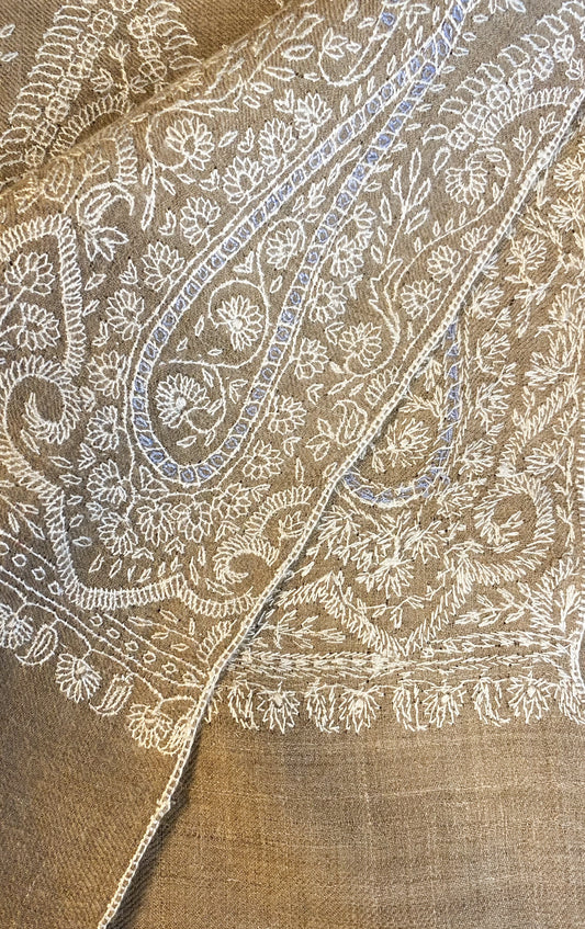 This pashmina is handcrafted with 100% cashmere on a handloom in Srinagar, India. The shawl is embellished with exquisite Sozni embroidery, featuring intricate patterns in white highlighted with subtle shades of light blue, giving it a distinct and sophisticated character. It's a piece of wearable art that brings the luxury and heritage to your wardrobe.