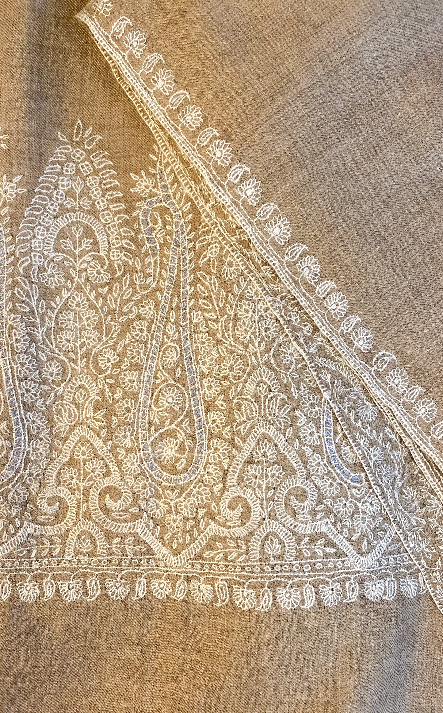 This pashmina is handcrafted with 100% cashmere on a handloom in Srinagar, India. The shawl is embellished with exquisite Sozni embroidery, featuring intricate patterns in white highlighted with subtle shades of light blue, giving it a distinct and sophisticated character. It's a piece of wearable art that brings the luxury and heritage to your wardrobe.