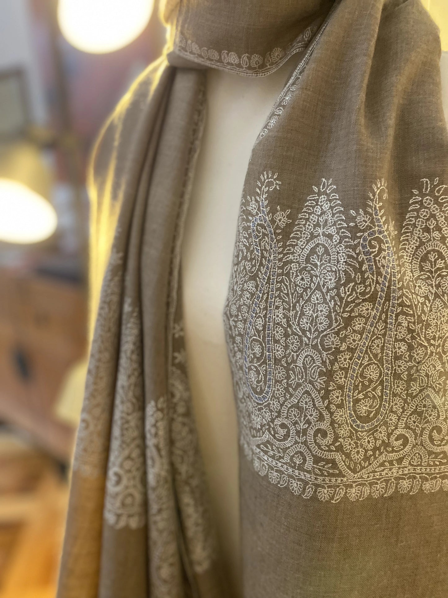 This pashmina is handcrafted with 100% cashmere on a handloom in Srinagar, India. The shawl is embellished with exquisite Sozni embroidery, featuring intricate patterns in white highlighted with subtle shades of light blue, giving it a distinct and sophisticated character. It's a piece of wearable art that brings the luxury and heritage to your wardrobe.