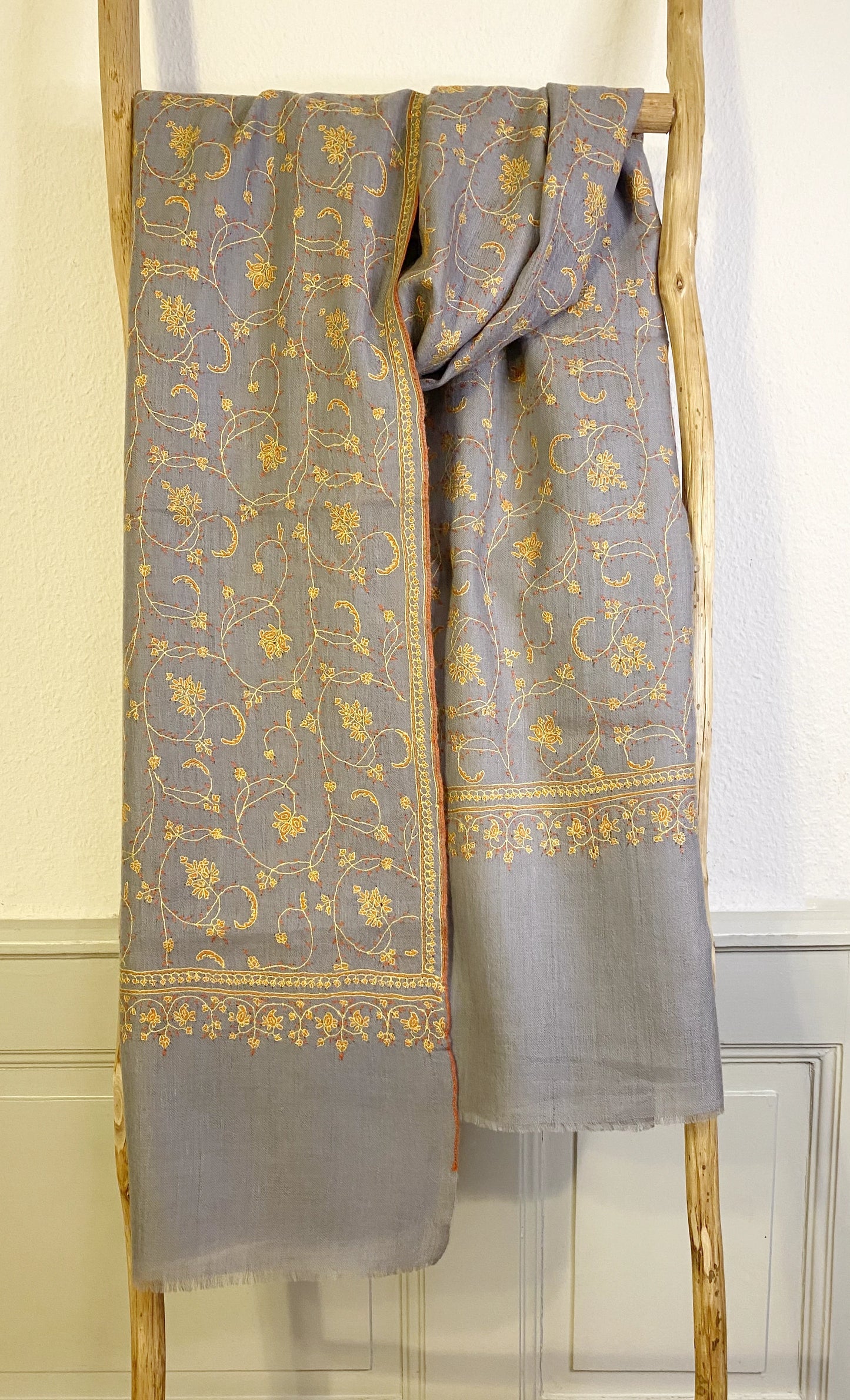 Luxuriously crafted and exquisitely detailed, this jaalidar pashmina stole stands as a statement of elegance and sophistication. At 70x200 cm and a mere 120 grams, it epitomizes luxury in every fiber. The stole, woven from the rare Yangir wool of the Himalayan Ibex, promises unparalleled softness. Its soft grey canvas, enriched with intricate yellow embroidery, reflects regal finesse and is a prized addition to any luxury collection.