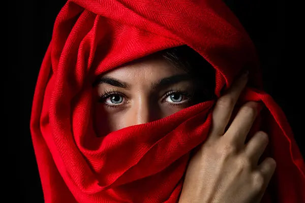 Women wearing on head and face Laal's exquisite red cashmere scarf. 