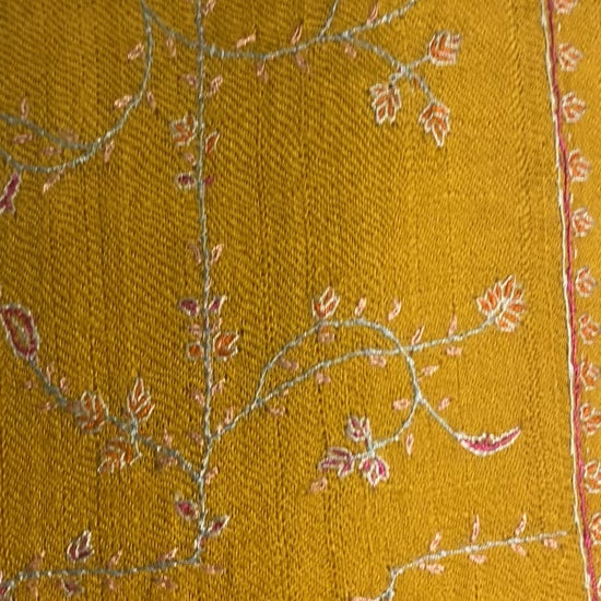 Exquisite Pashmina stole crafted from rare Yangir yarn, sourced from Himalayan Ibex, measuring 70x200 cm. Features a warm mustard base with hand-embroidered, deep burgundy Jaalidar motifs, creating a lace-like design that radiates elegance. Its exceptional softness and subtle sheen highlight the interplay of colors and textures, making it versatile for both semi-casual and formal wear.