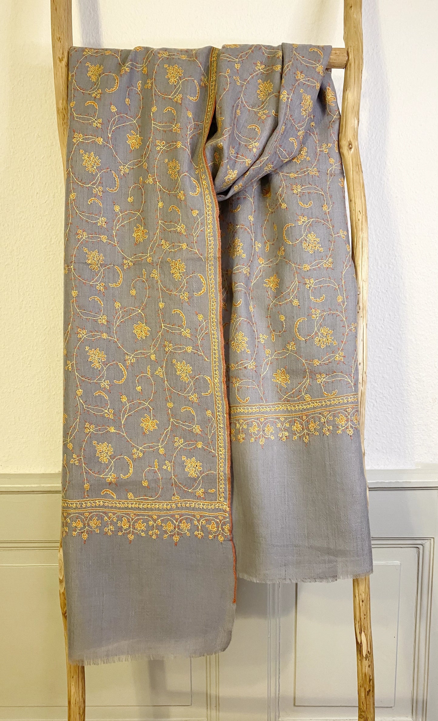 Luxuriously crafted and exquisitely detailed, this jaalidar pashmina stole stands as a statement of elegance and sophistication. At 70x200 cm and a mere 120 grams, it epitomizes luxury in every fiber. The stole, woven from the rare Yangir wool of the Himalayan Ibex, promises unparalleled softness. Its soft grey canvas, enriched with intricate yellow embroidery, reflects regal finesse and is a prized addition to any luxury collection. 